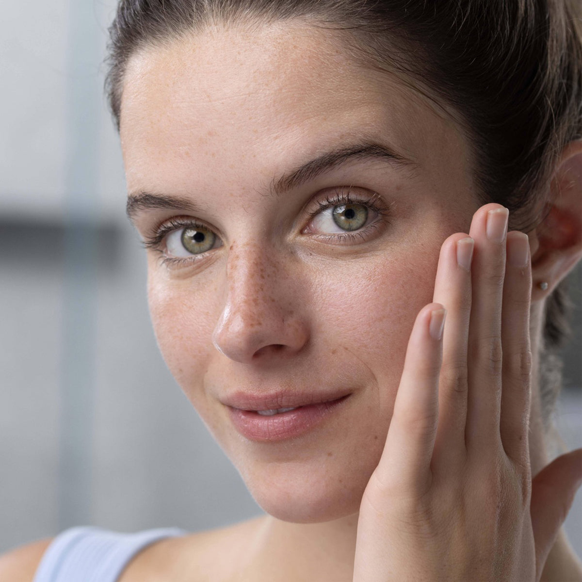 Donna con pelle fresca e luminosa che si tocca delicatamente il viso, primo piano per la routine di detersione PHYSIOPURE.