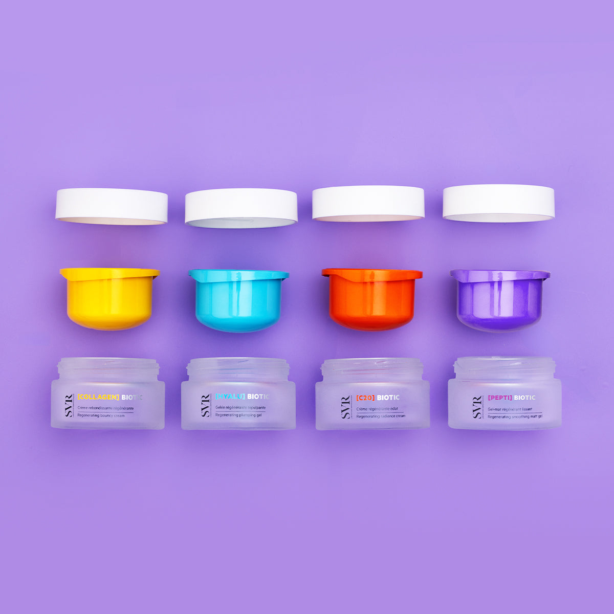 Quattro vasetti di crema SVR Biotic con tappi colorati, coperchi bianchi e contenitori in vetro satinato su sfondo viola.