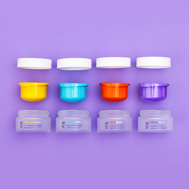 Quattro vasetti di crema viso SVR Biotic con tappi colorati e coperchi bianchi su sfondo viola, vista dall'alto.