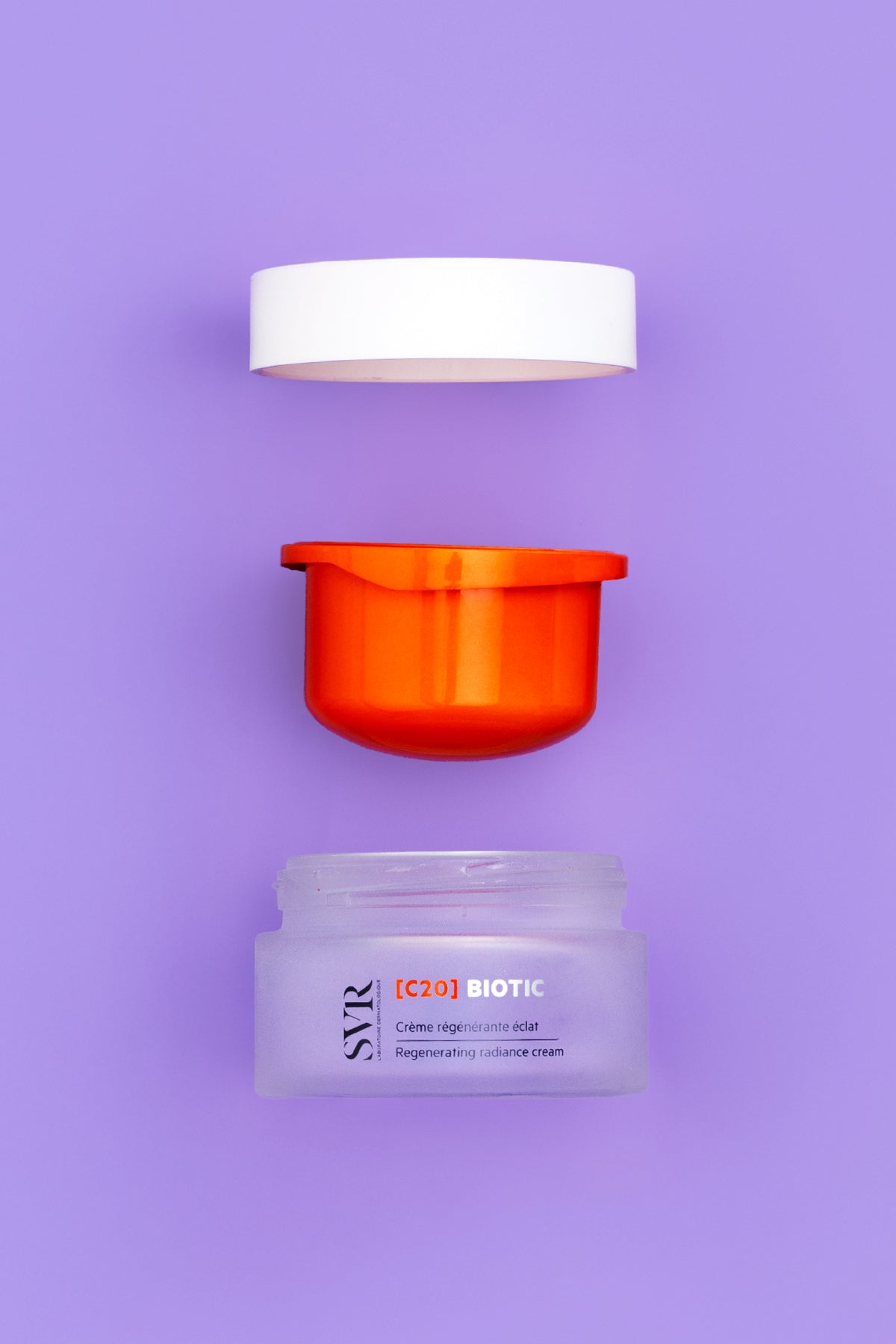 Crema viso SVR C20 Biotic in vasetto di vetro satinato con tappo bianco e inserto arancione su sfondo viola.