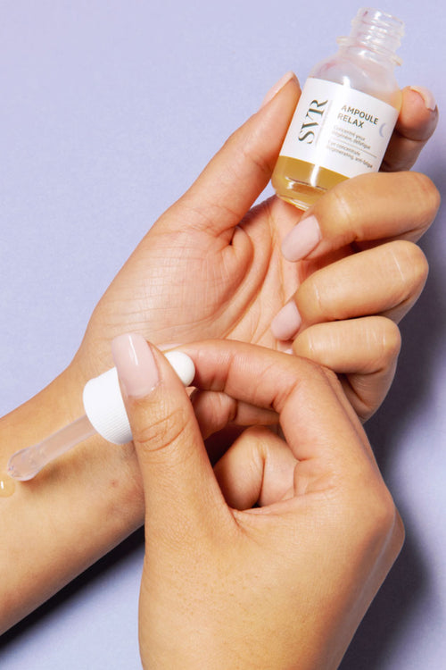 Siero notte SVR Ampoule Relax in flacone di vetro con contagocce applicato sulla pelle per mostrare la texture olio-gel.