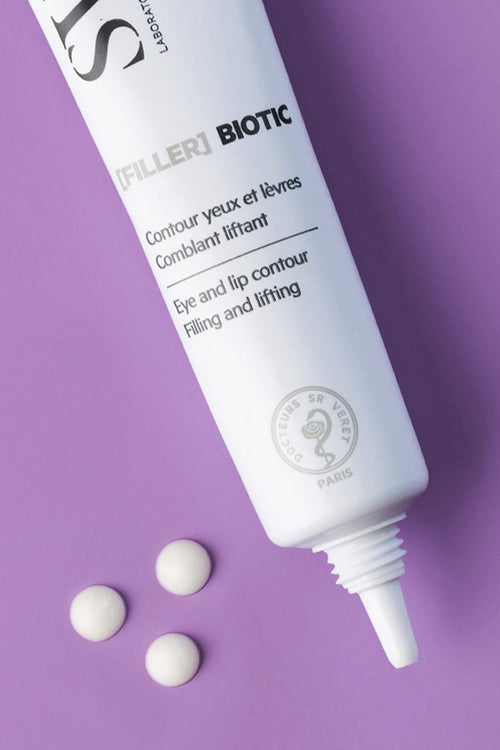 Tubo bianco di [FILLER] BIOTIC per contorno occhi e labbra con tre gocce di crema su sfondo viola.