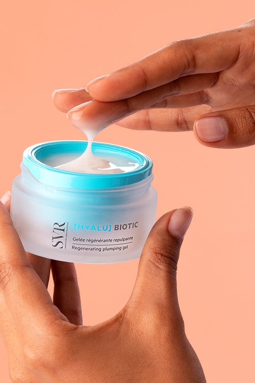 Vasetto di gel-crema SVR Hyalu Biotic con tappo azzurro tenuto tra le mani, mostrando la texture leggera e idratante del prodotto.