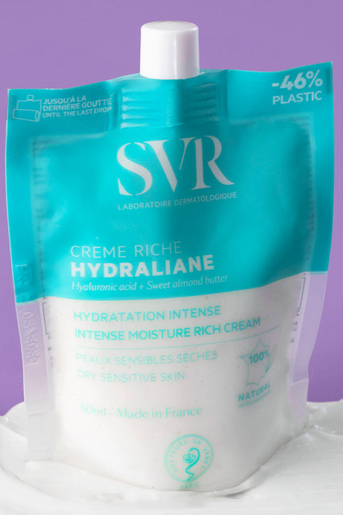 Confezione flessibile e riciclabile di SVR Hydraliane Crème Riche su una base di crema bianca, sfondo viola.