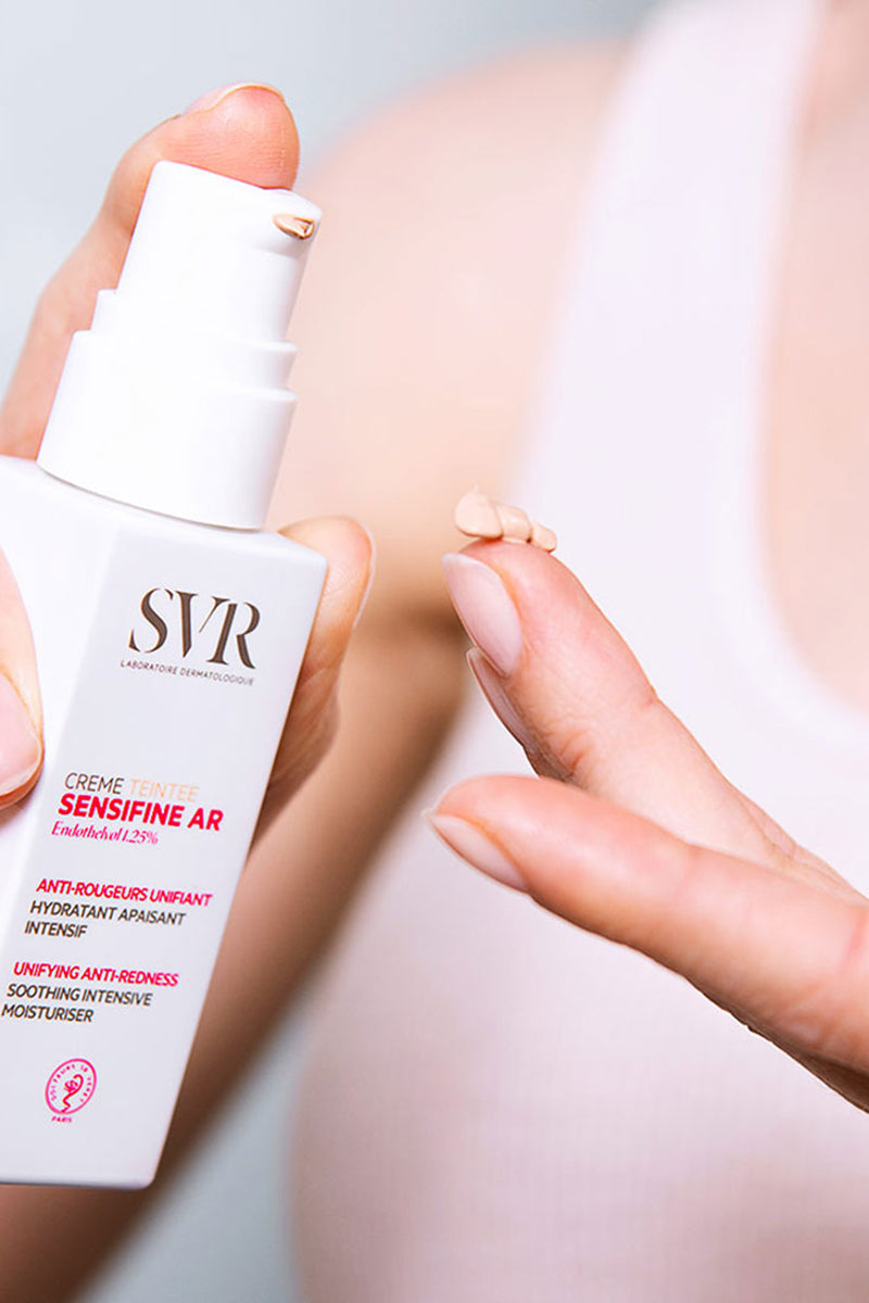 Flacone bianco SVR Sensifine AR Crème Teintée con dosatore a pompa e goccia di crema colorata sul dito.