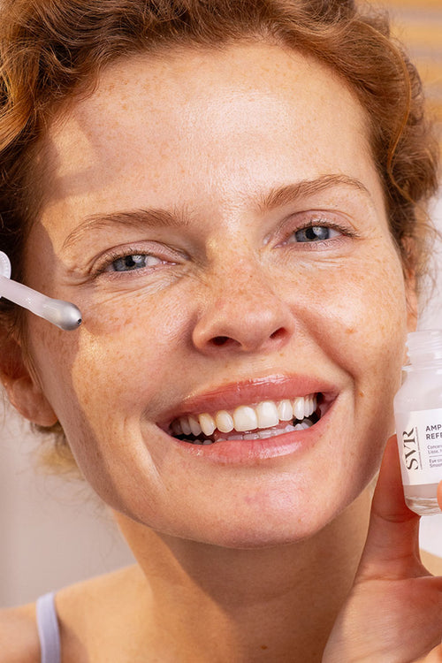 Donna sorridente applica il siero contorno occhi SVR Ampoule Refresh con l'innovativo applicatore in metallo rinfrescante.