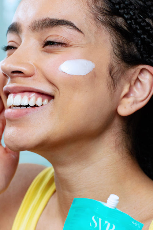 Donna sorridente applica la crema idratante Hydraliane SVR sul viso con il nuovo packaging eco-sostenibile in plastica.