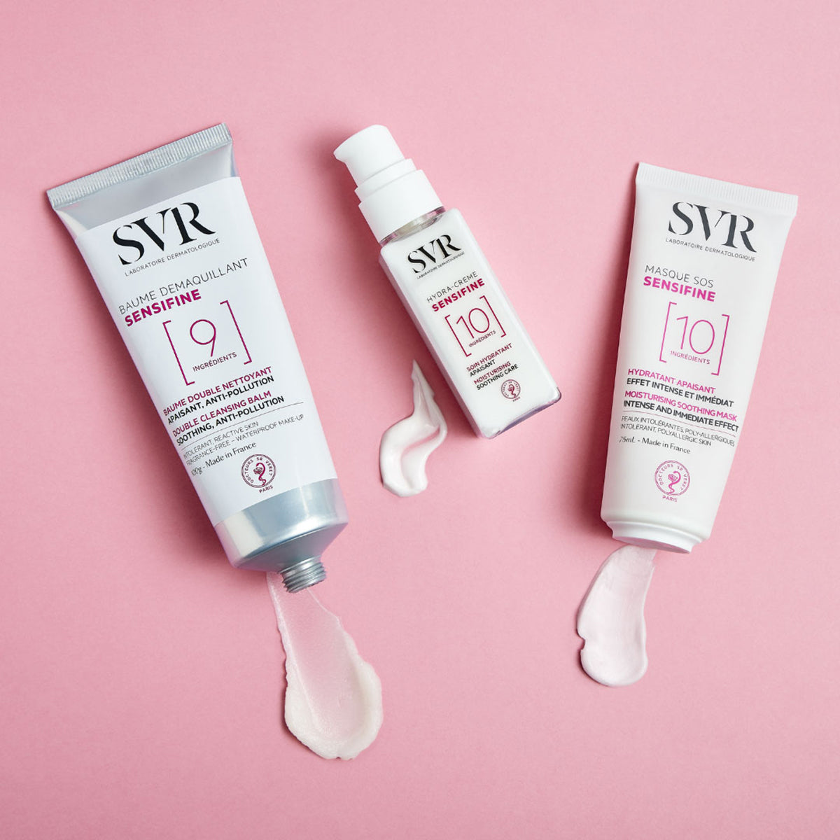 Tre prodotti SVR Sensifine bianchi con texture cremosa rosa su sfondo rosa, inclusi maschera, crema e balsamo detergente.
